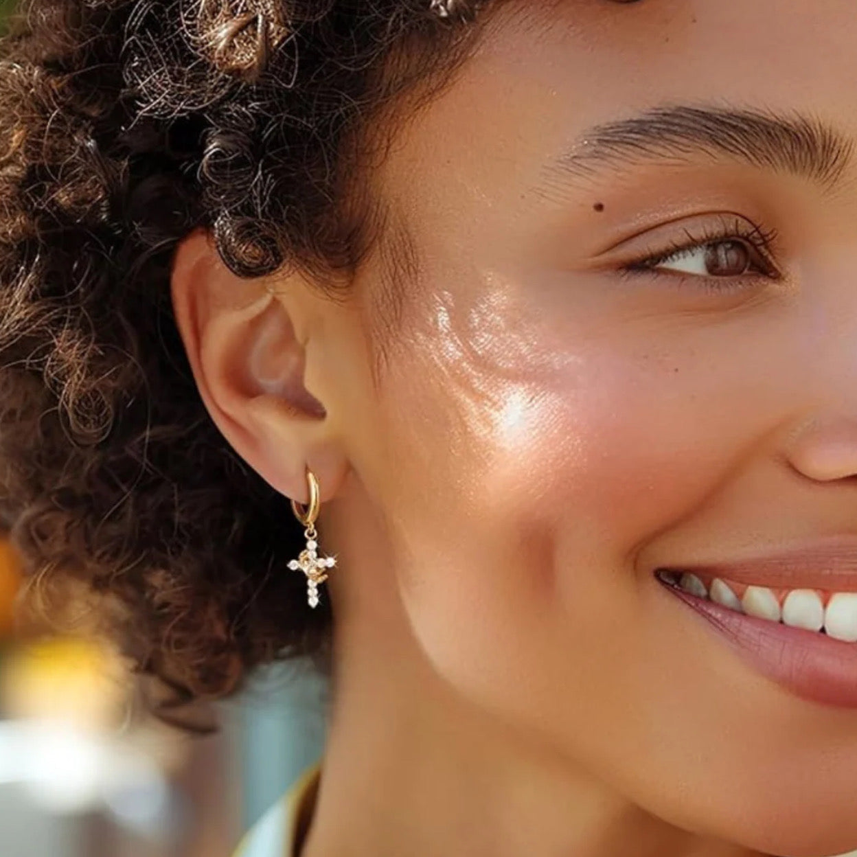 Close-up of a woman wearing the Gold Cross Crown earrings with cubic zirconia stones.