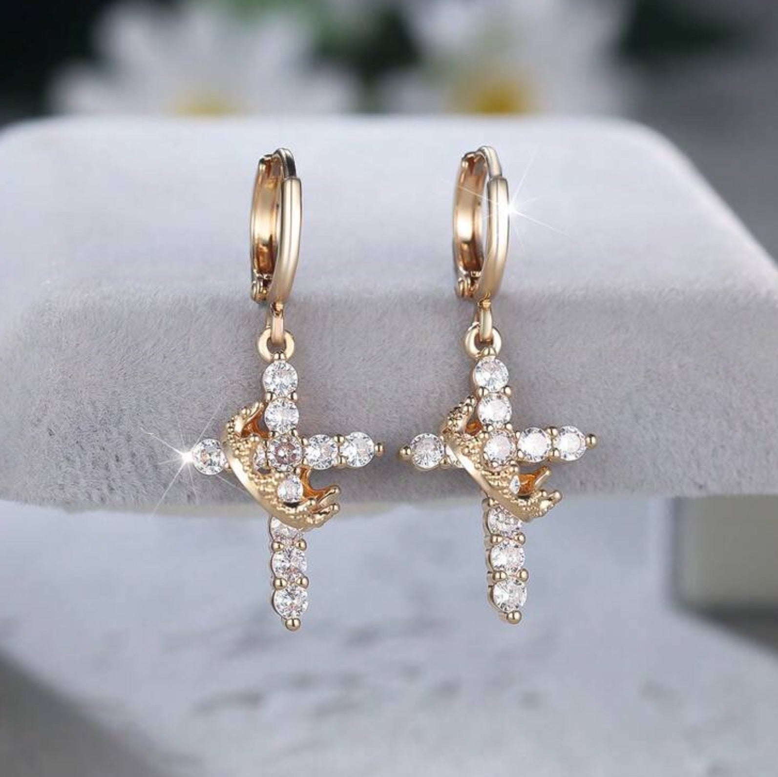 Gold Cross Crown earrings with cubic zirconia stones on a white stand.