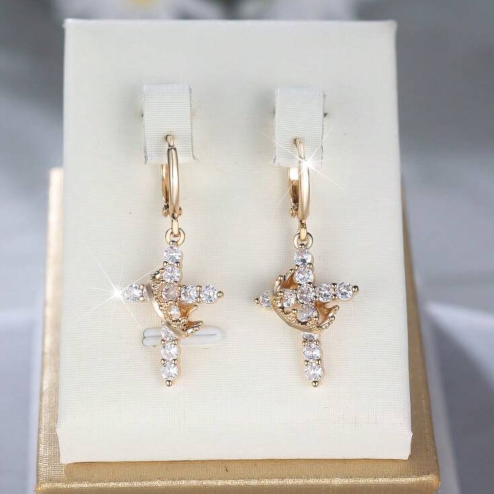 Gold Cross Crown earrings with cubic zirconia stones on a white display card.