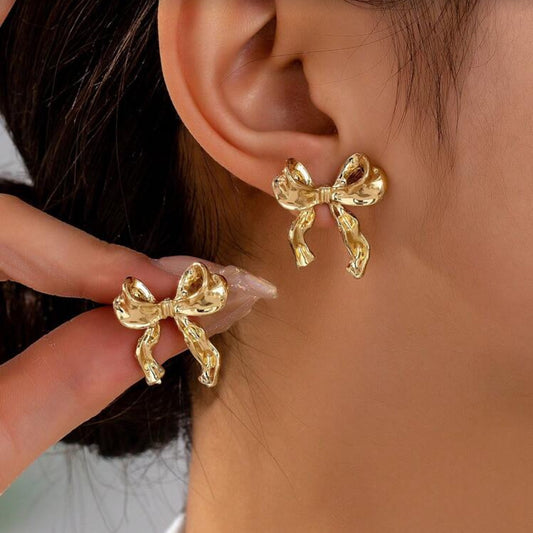 Gold Bow Ribbon Earrings worn by a woman