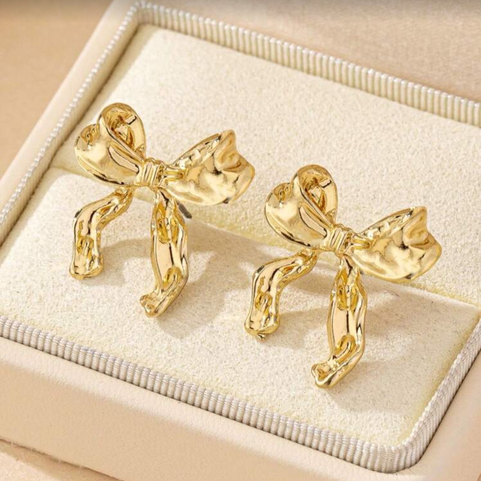 Gold Bow Ribbon Earrings on a display