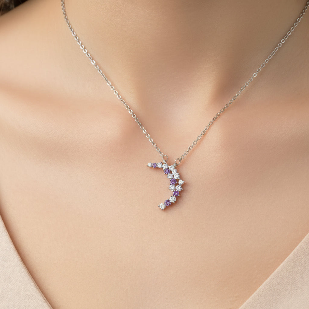 Purple & Silver Crescent Moon Necklace with purple and clear gemstones on a light blue background