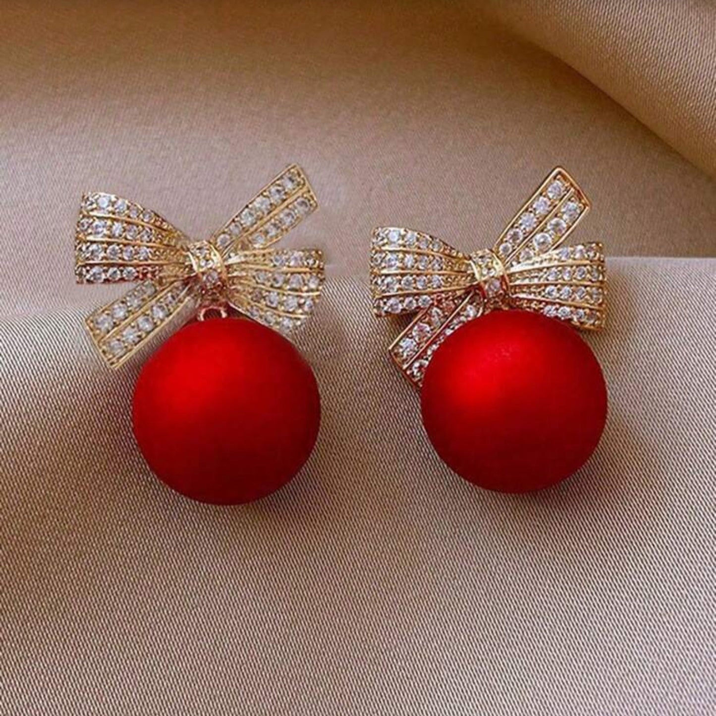 Red Ornament Bow Earrings on fabric background