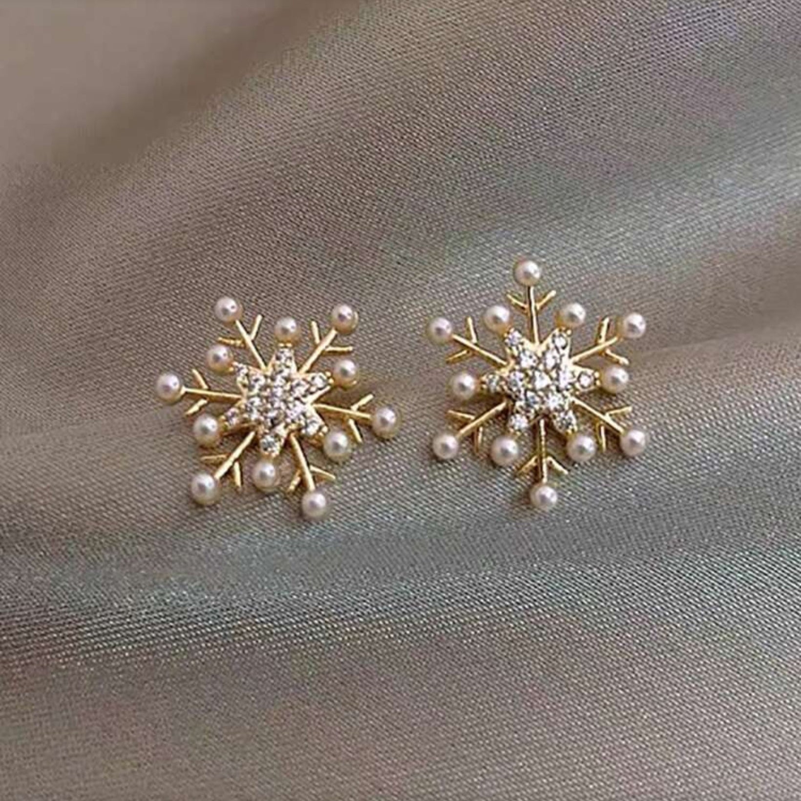 Snowflake Pearl Earrings with pearl and crystal details on a gray fabric background