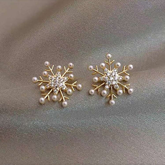 Snowflake Pearl Earrings with pearl and crystal details on a gray fabric background