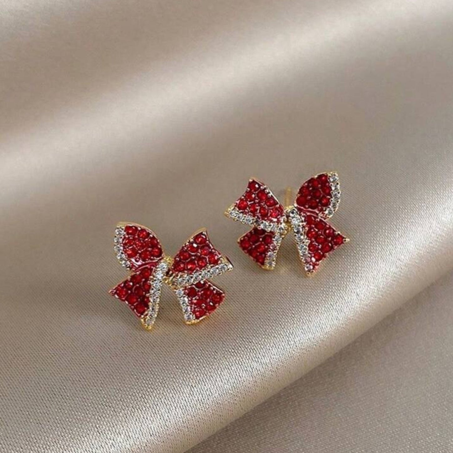 Red Rhinestone Bow Earrings on a beige fabric background