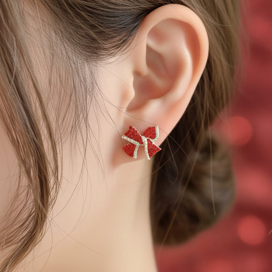 Close-up of an ear wearing Red Rhinestone Bow Earrings with a neutral background
