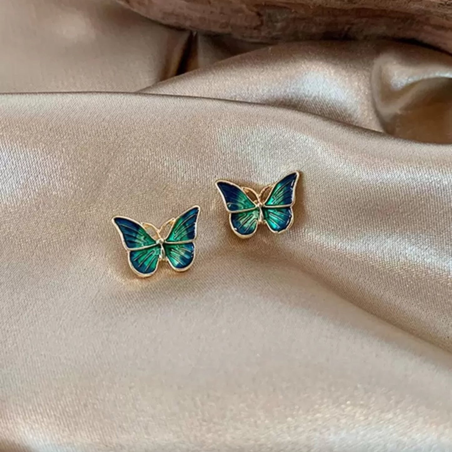 Blue & Green Butterfly Earrings on a beige fabric background