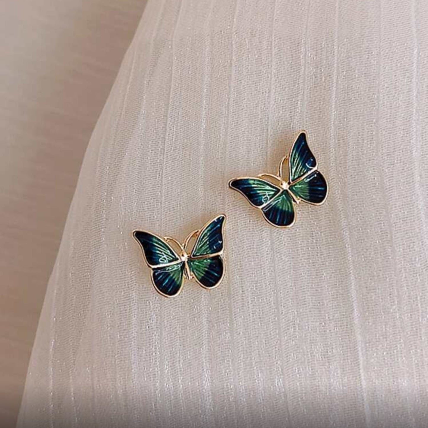 Blue & Green Butterfly Earrings on a light fabric background