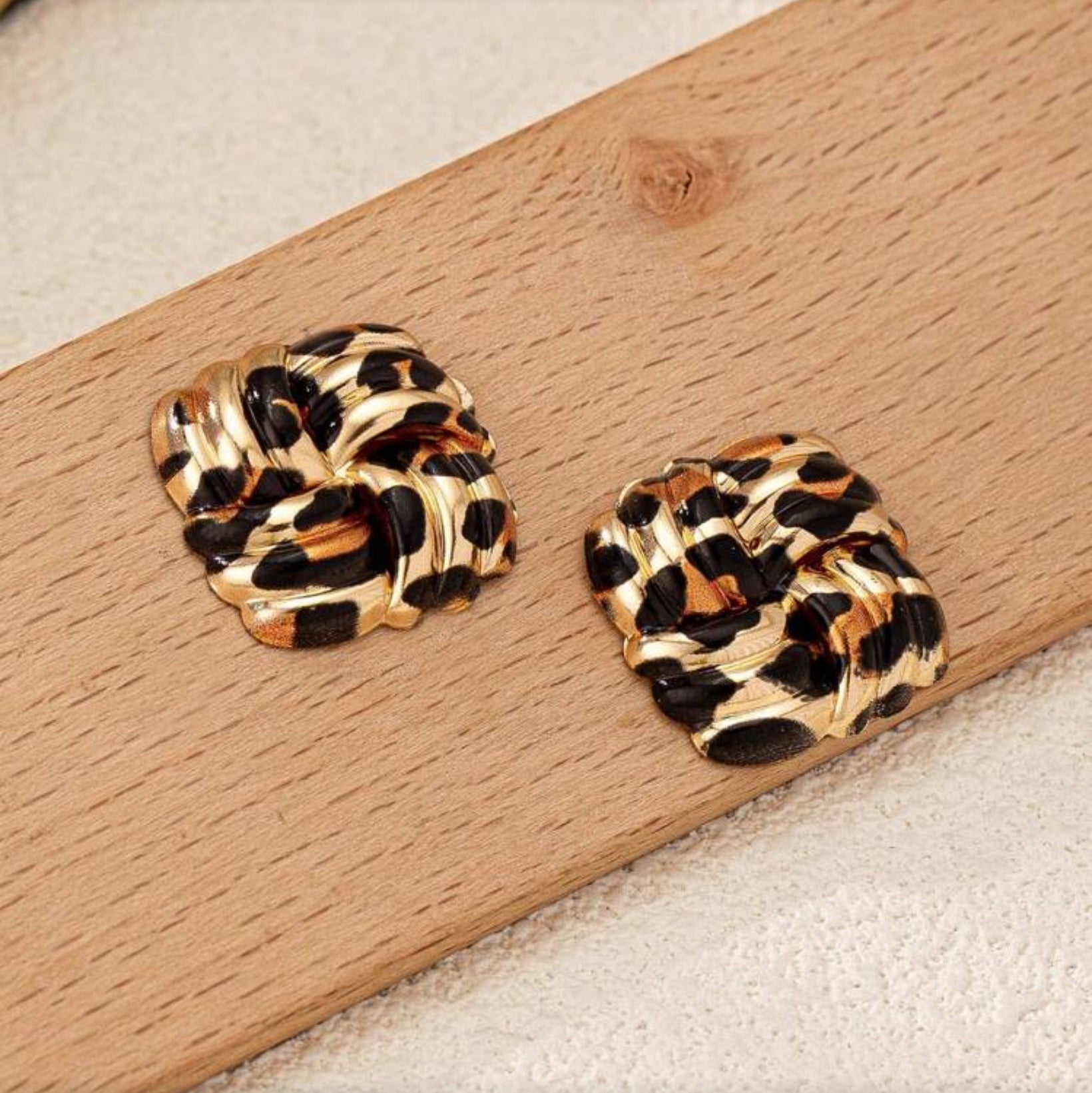 Leopard Square Knot Earrings on a wooden surface