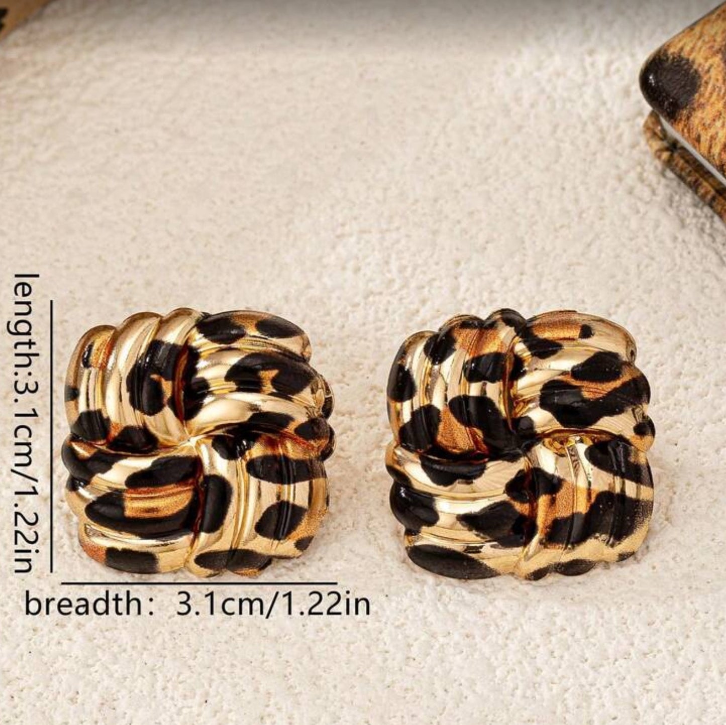 Leopard Square Knot Earrings with gold accents on a textured beige background.