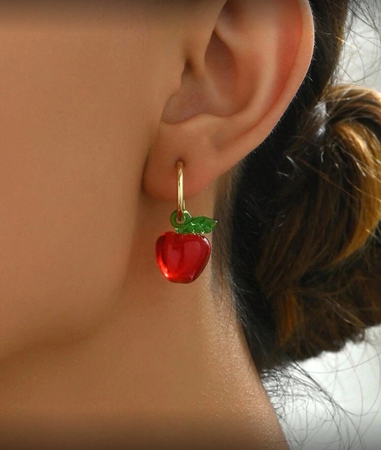 Red Apple Hoop Earrings on a person's ear
