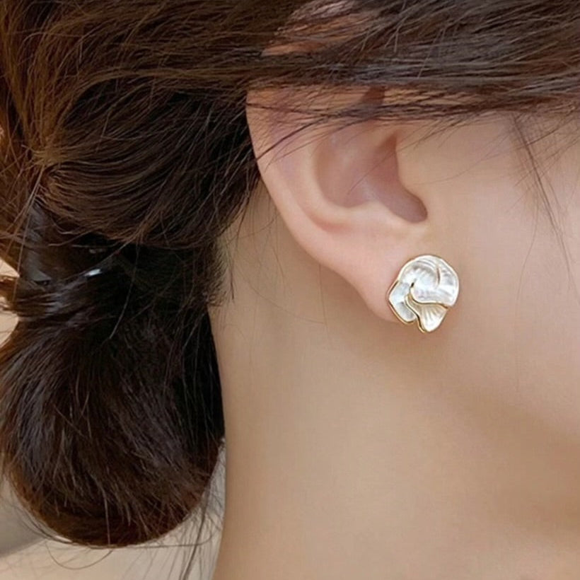 Close-up of Golden Edge Pearl Earrings with pearl-like petal design and gold trim with hair styled in a bun.