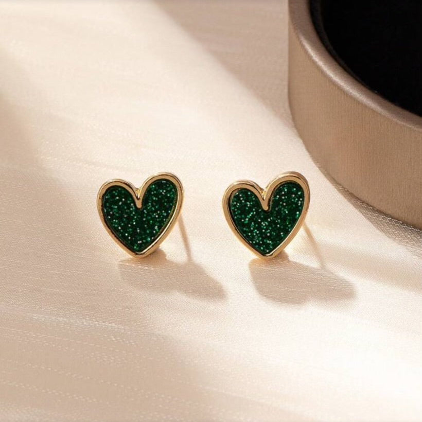 Green Glitter Heart Earrings on a light surface with a cup in the background