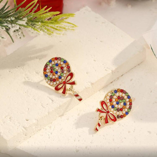Holiday Sparkle Lollipop Earrings on a white box with Christmas decorations in the background.