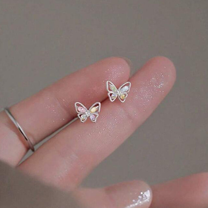 Pastel Crystal Butterfly Earrings on a finger against a neutral background
