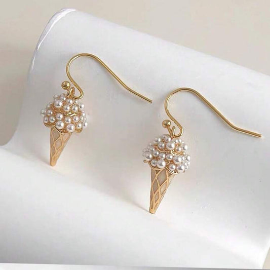 Gold ice cream cone-shaped earrings with pearl details on a white surface
