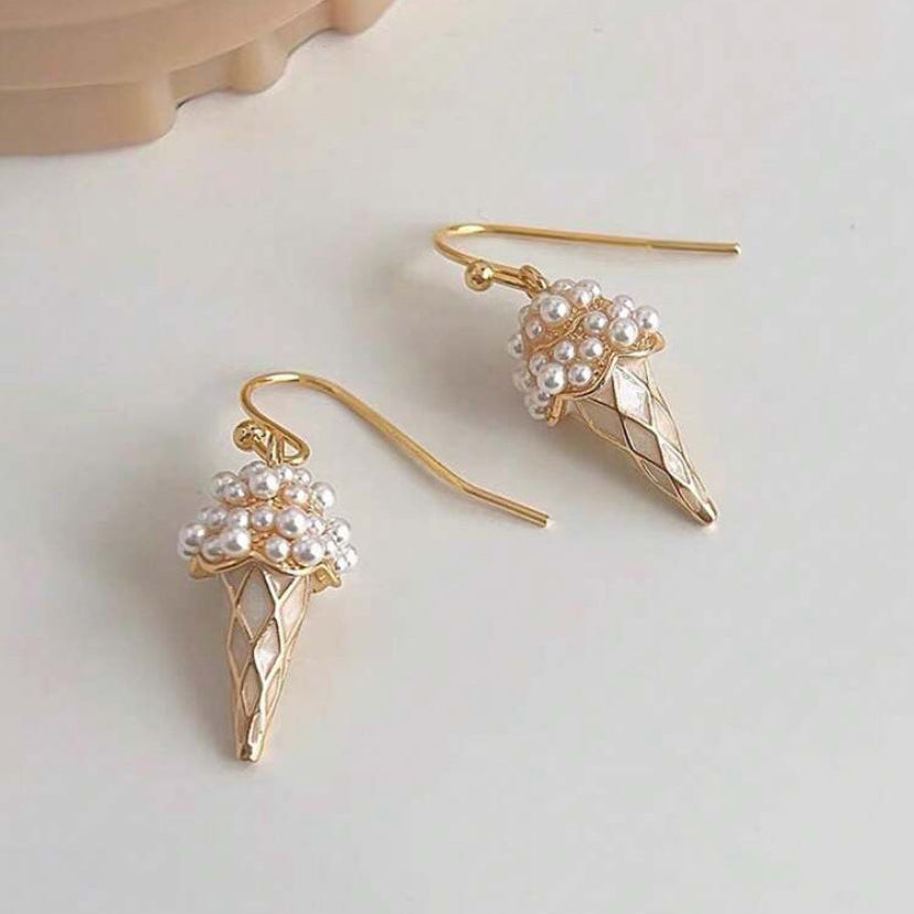 Gold ice cream cone earrings with pearl decorations on a light background