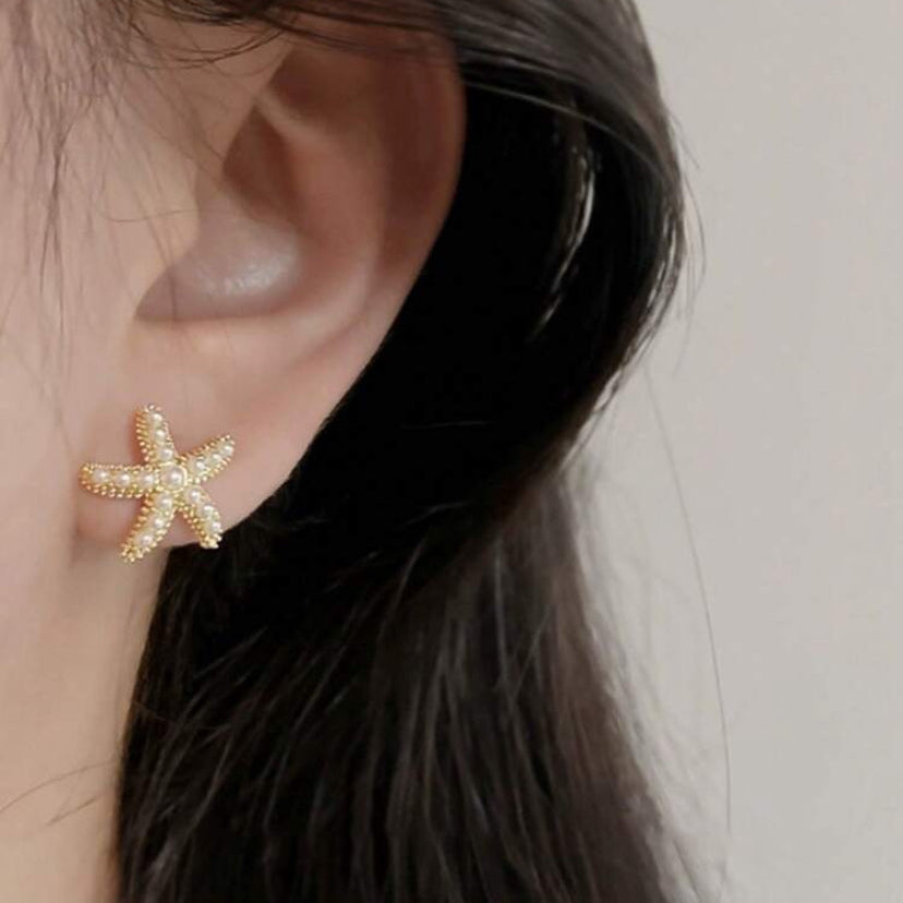 Gold starfish earring worn by a person with dark hair.