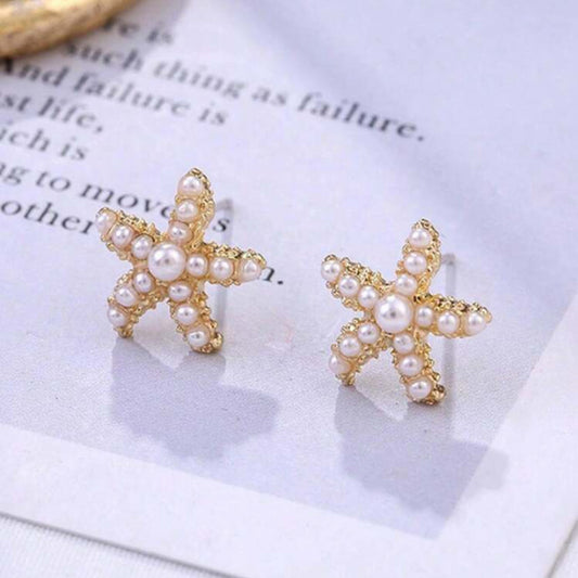 Starfish-shaped earrings with pearl details on a white surface.