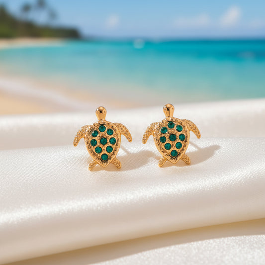 Green Crystal Sea Turtle Earrings on fabric on a beach