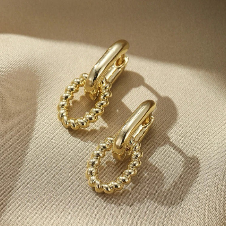 Pair of gold hoop earrings on a beige fabric background
