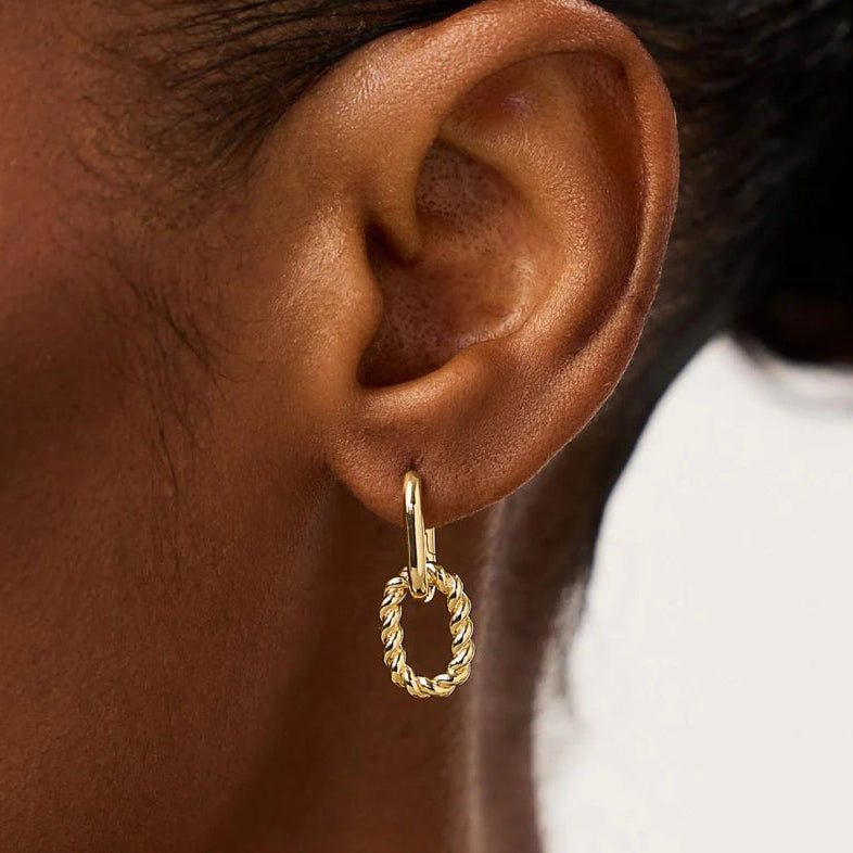 Close-up of an ear wearing a gold hoop earring with a blurred background