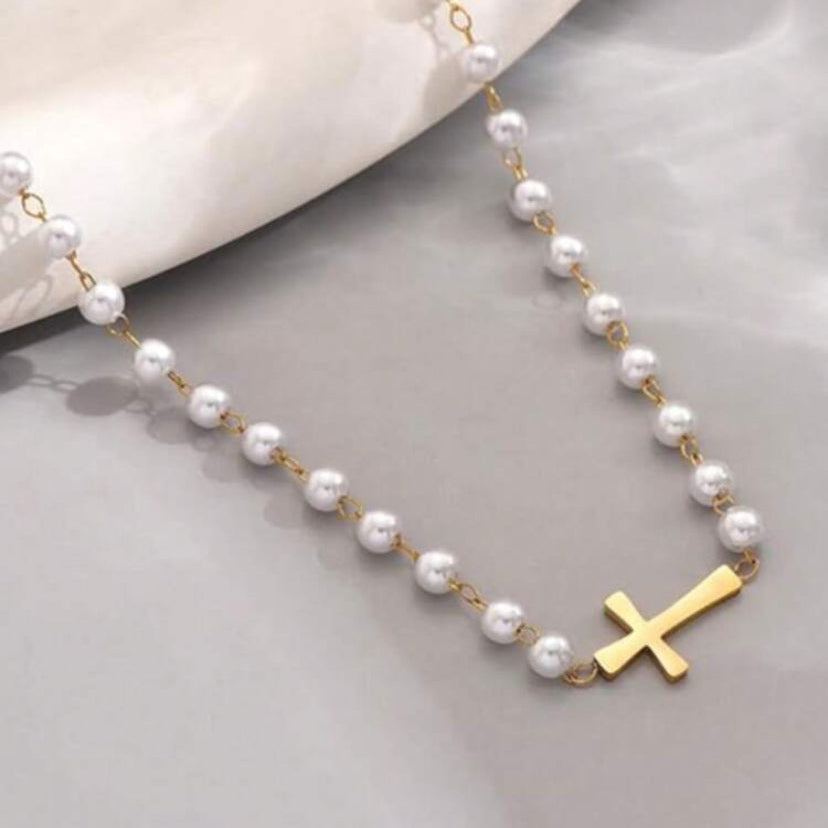 Gold Cross Pearl Necklace on a light gray surface