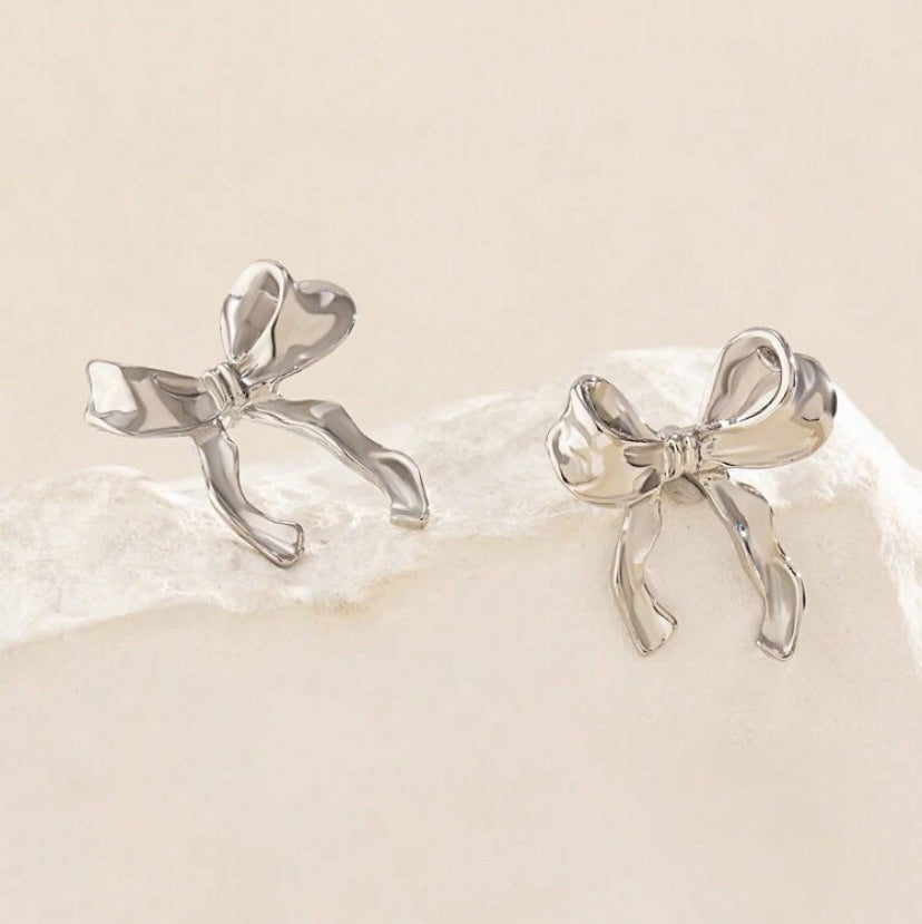 Silver Bow Ribbon Earrings on white rock