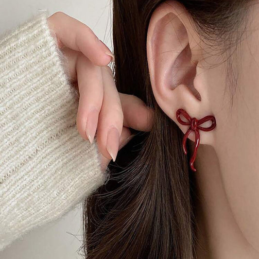 Close-up of a person wearing a Crimson Bow Earrings.