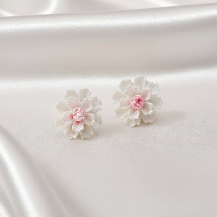 White flower earrings on a satin surface