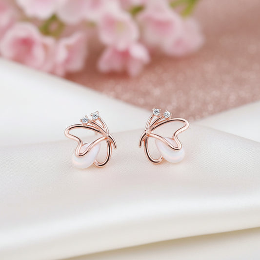 Rose Gold Butterfly Pearl Earrings on a pink background