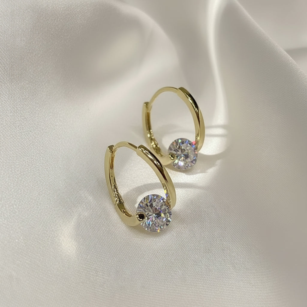 Gold Zircon Drop Hoop Earrings with clear gemstones on a light fabric background
