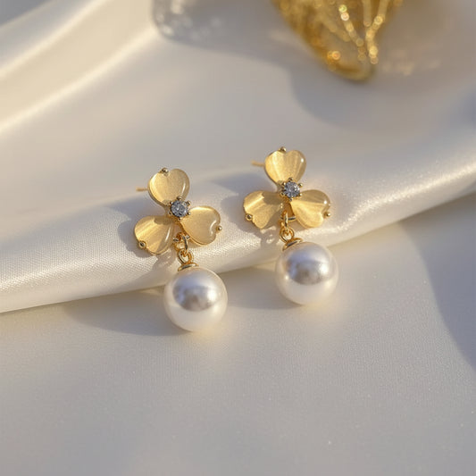 Luminous Gold Clover Pearl Drop Earrings on a white fabric