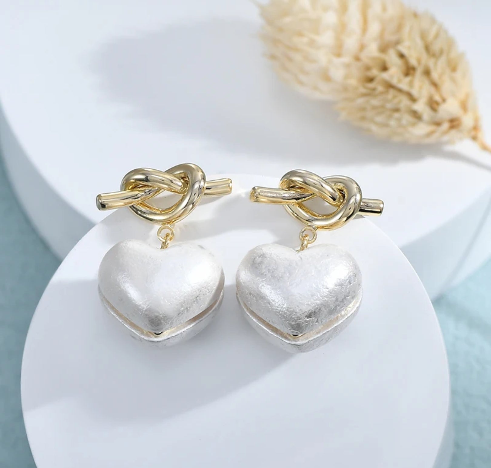 A pair of heart-shaped earrings with bowknot details, displayed on a white surface.