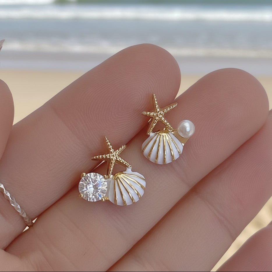Starfish Pearl & Crystal Earrings held between fingers against a blurred background