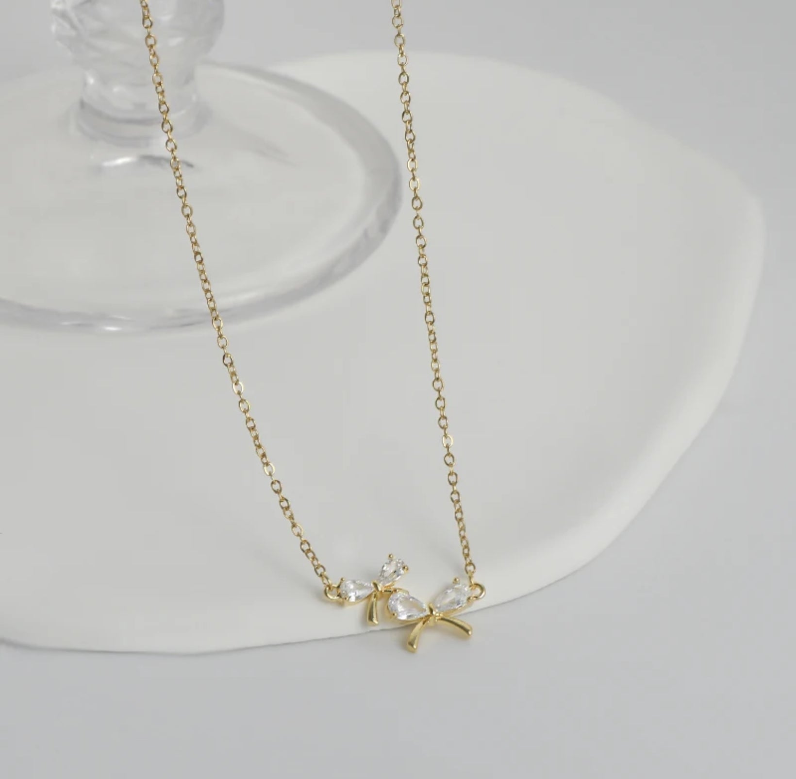 Zircon Bow Necklace featuring a sparkling bow pendant on an adjustable 17-19" chain, all white background showing gold chain.
