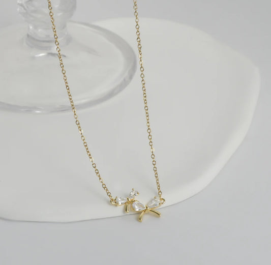 Zircon Bow Necklace featuring a sparkling bow pendant on an adjustable 17-19" chain, all white background showing gold chain.