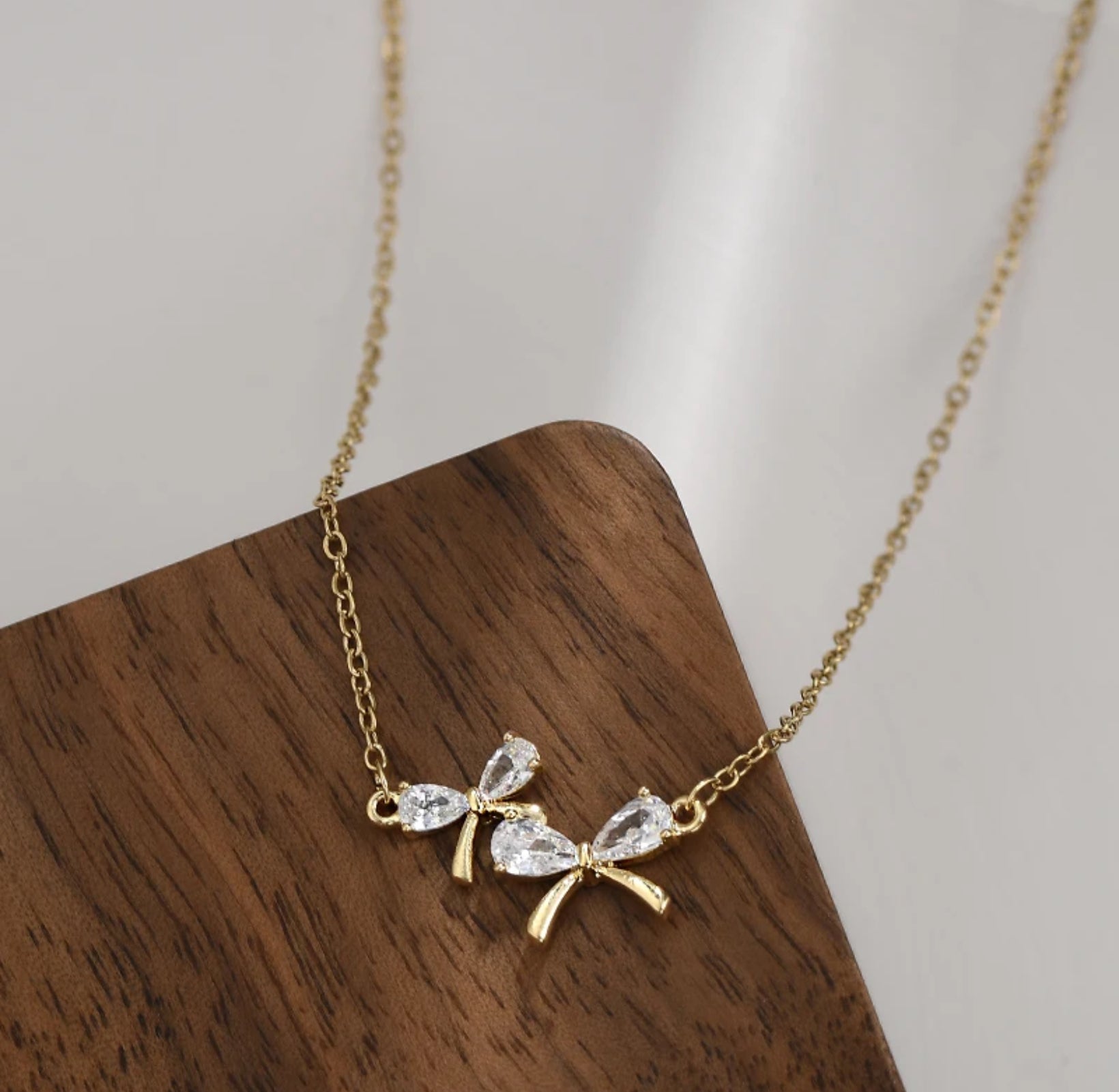 Zircon Bow Necklace featuring a sparkling bow pendant on an adjustable 17-19" chain.