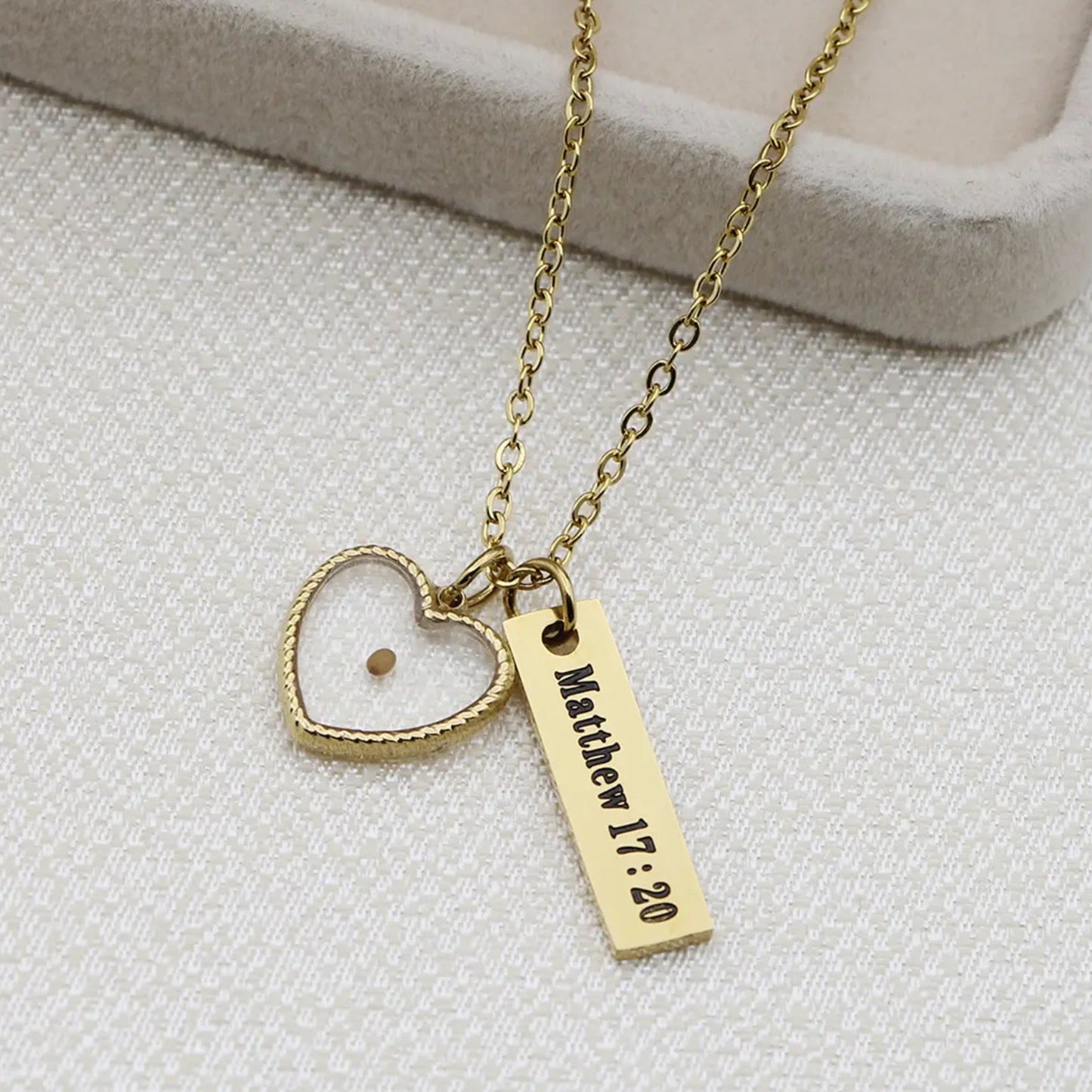 A gold-plated Mustard Seed Heart Necklace with a heart-shaped charm and an engraved tag on a chain, displayed on a white background.