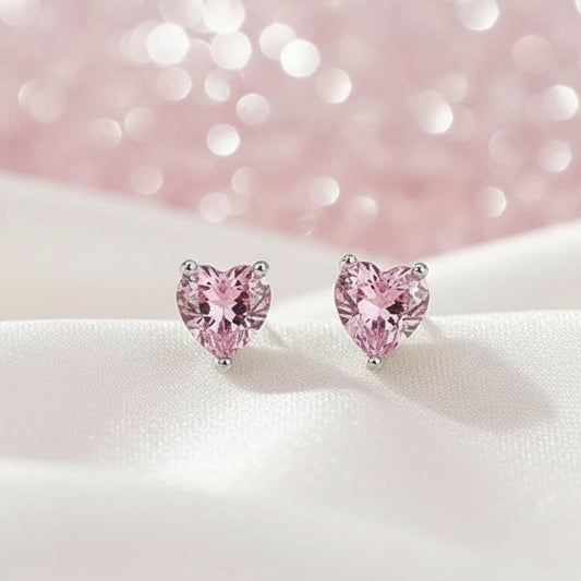 Heart-shaped pink earrings on a beige fabric background