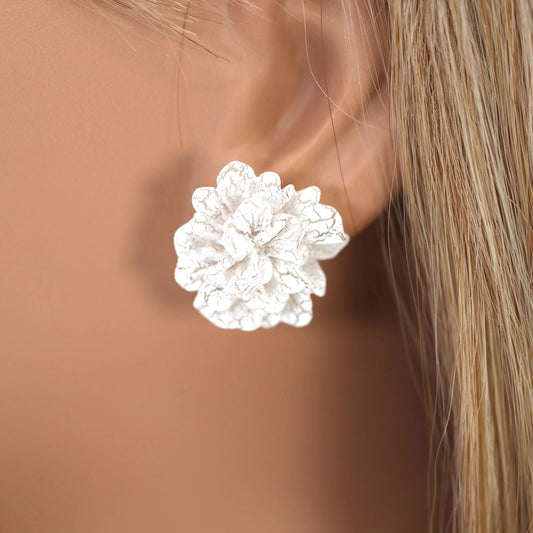 White Bloom Statement Stud Earrings on a person's ear with a blurred background