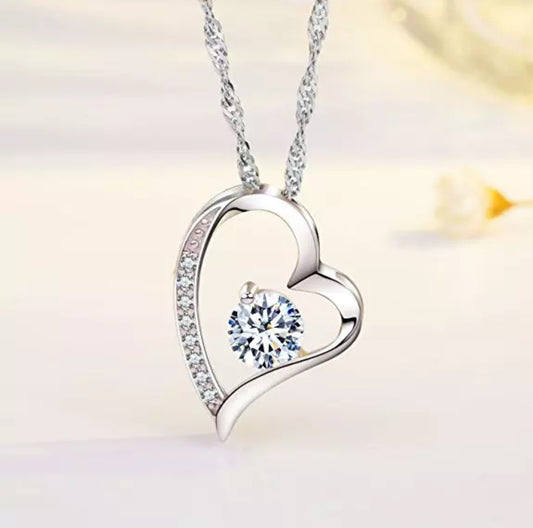 A silver heart-shaped necklace with a cubic zirconia embellishment in the center.