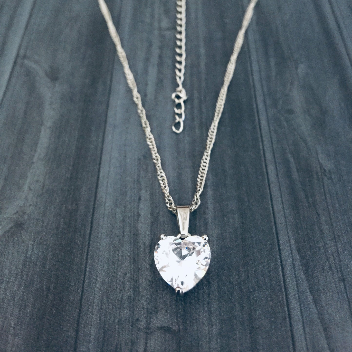 Necklace with a heart-shaped crystal pendant on a dark wooden surface
