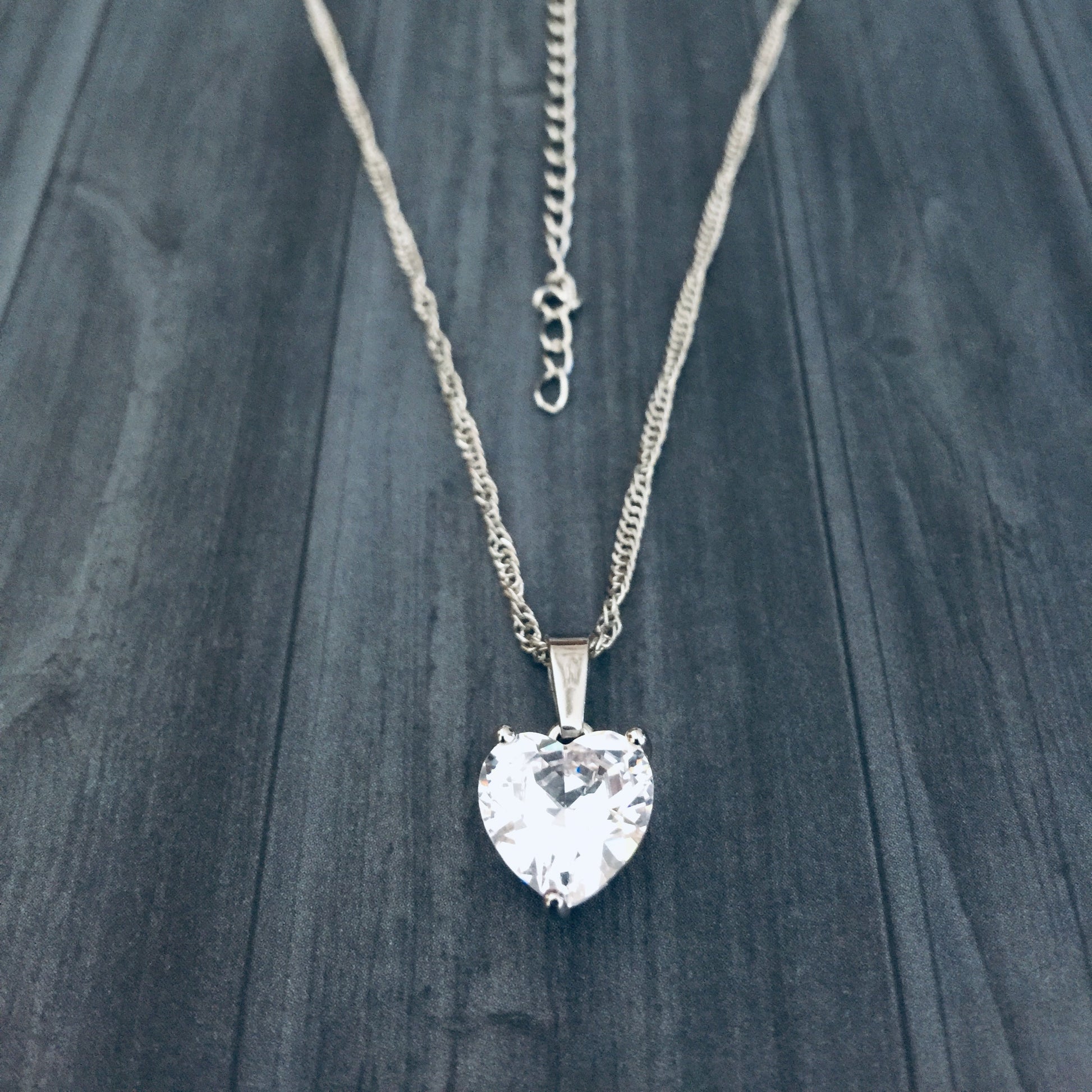 Necklace with a heart-shaped crystal pendant on a dark wooden surface