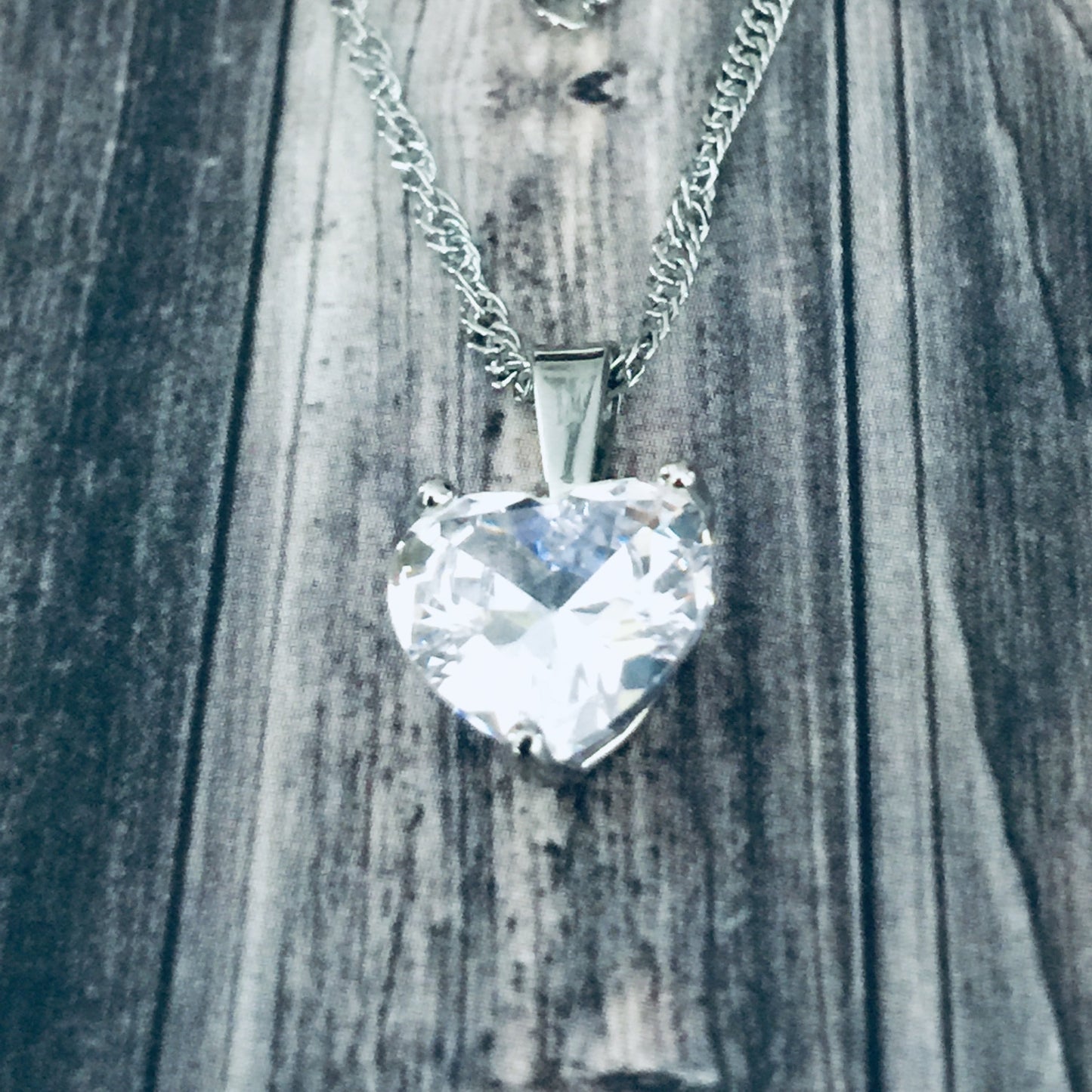 Heart-shaped crystal pendant on a chain against a wooden background