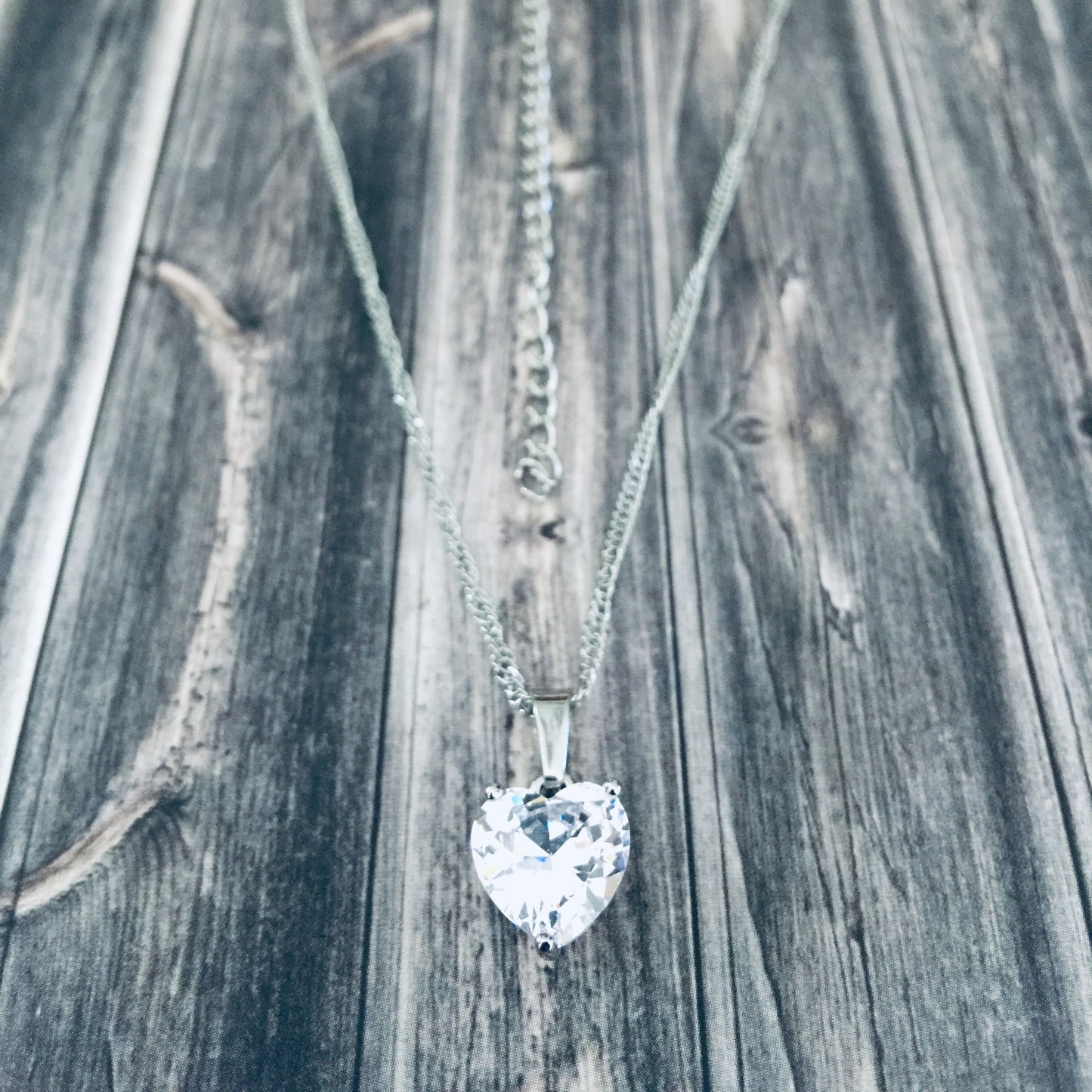 Adjustable silver necklace with a heart-shaped cubic zirconia pendant.
