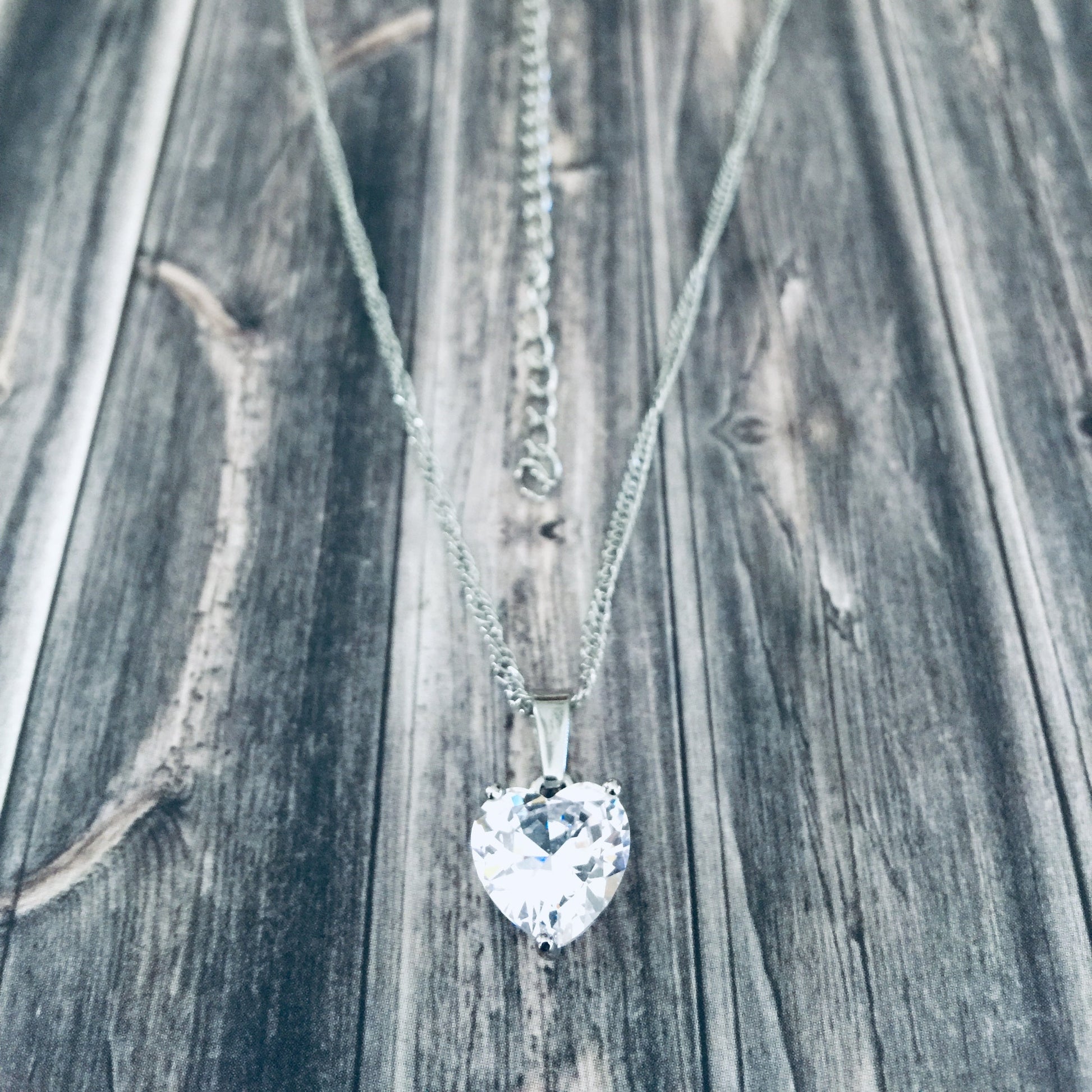 Adjustable silver necklace with a heart-shaped cubic zirconia pendant.