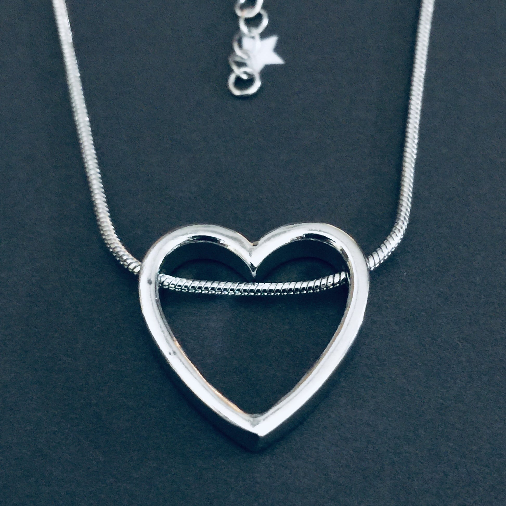 Silver heart-shaped necklace on a dark background