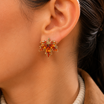 A close-up of a person's ear wearing a Amber Crystal Maple Leaf Earrings